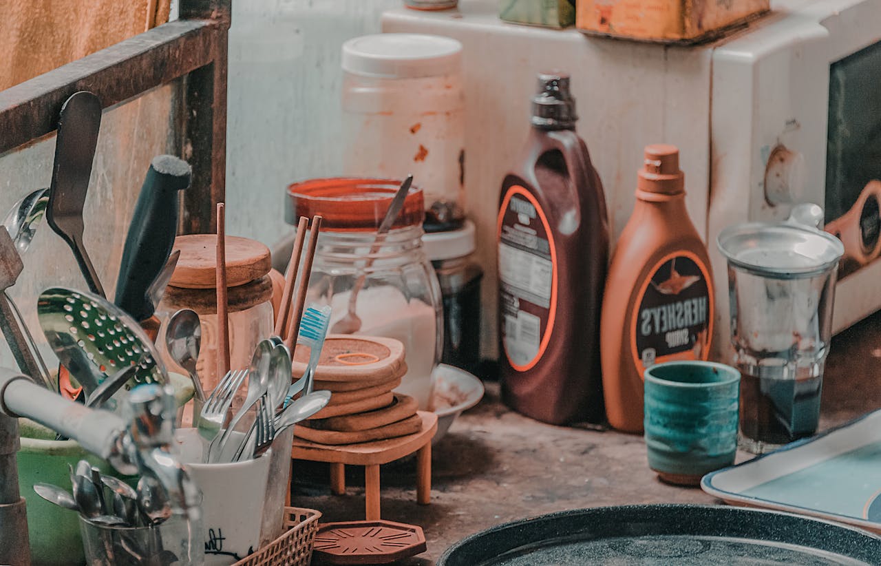 A cluttered kitchen counter filled with utensils, jars, and condiments, creating a rustic and homely vibe.